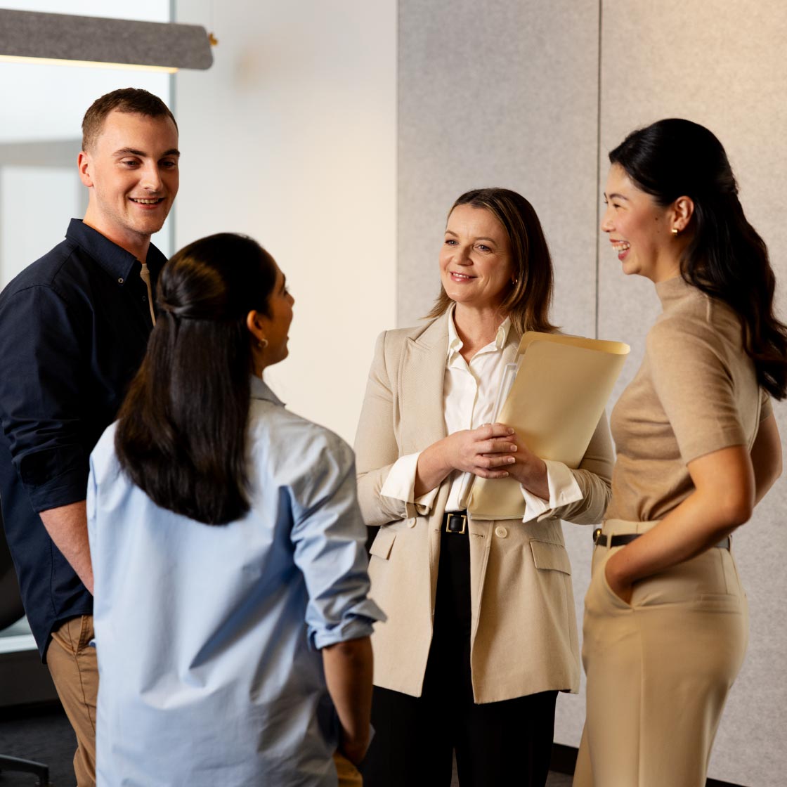 A group of four people, students and a teacher, talk together.
