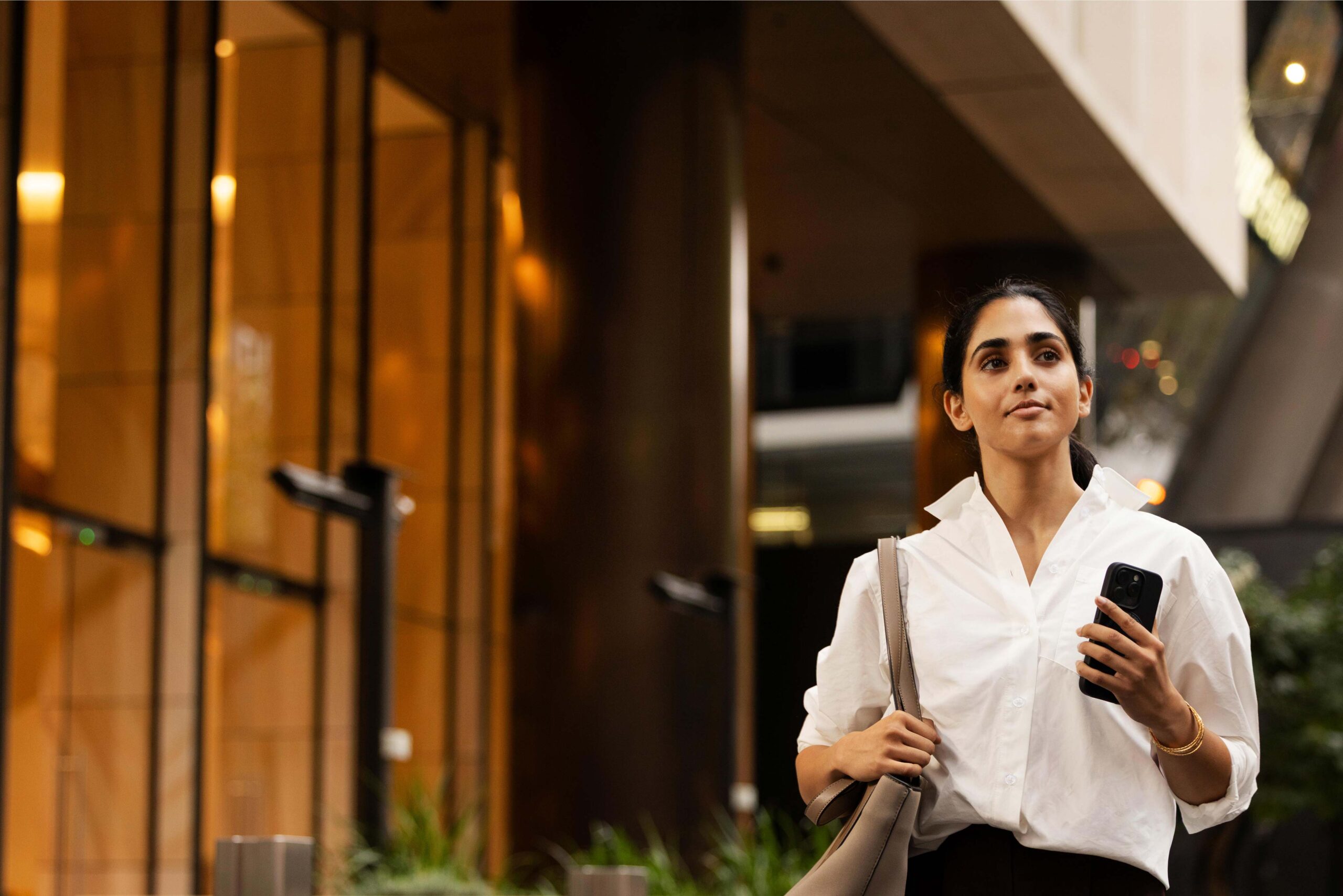 A woman walks confidently along a city street.